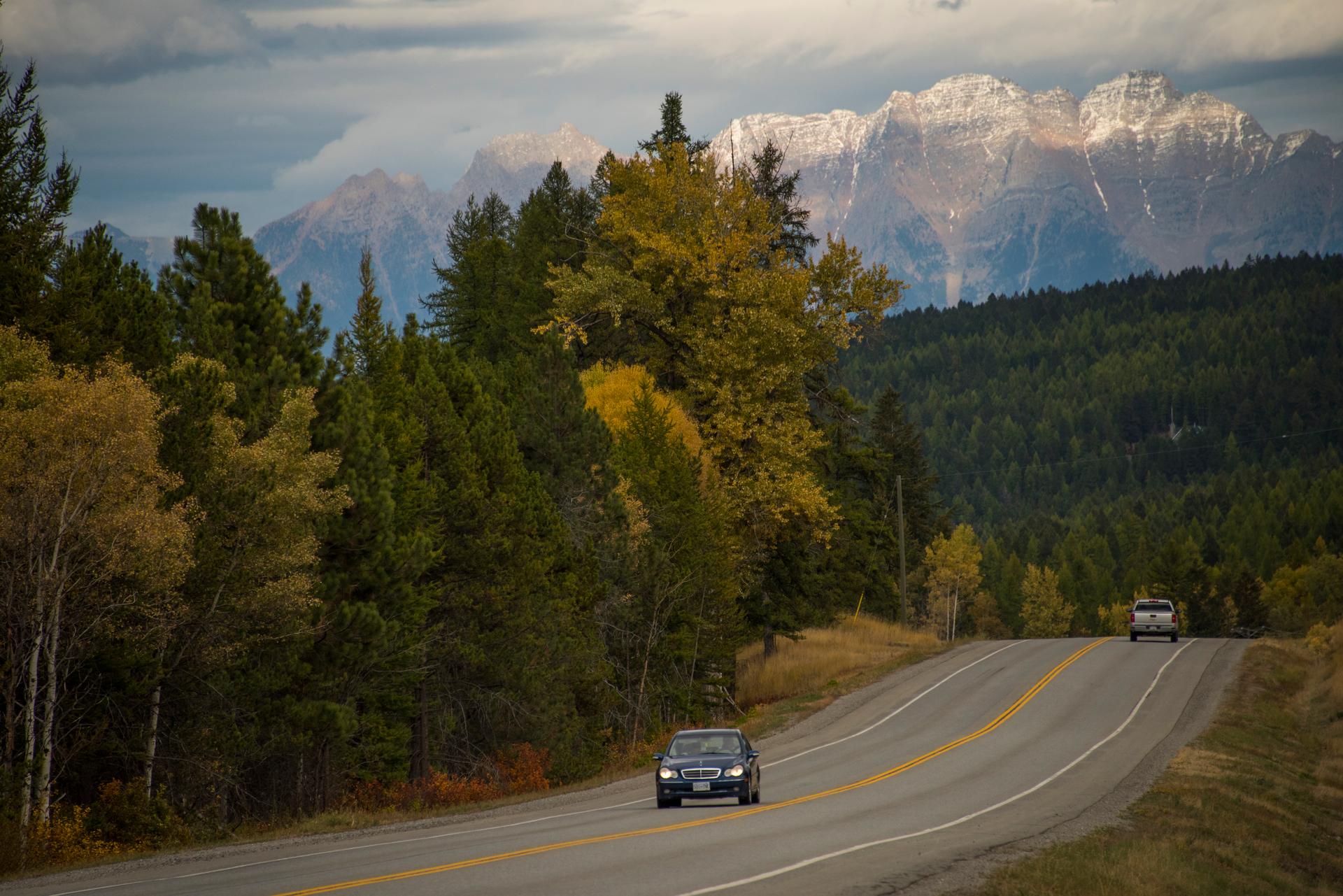 Cars driving on Highway 3, with mountains in the background.