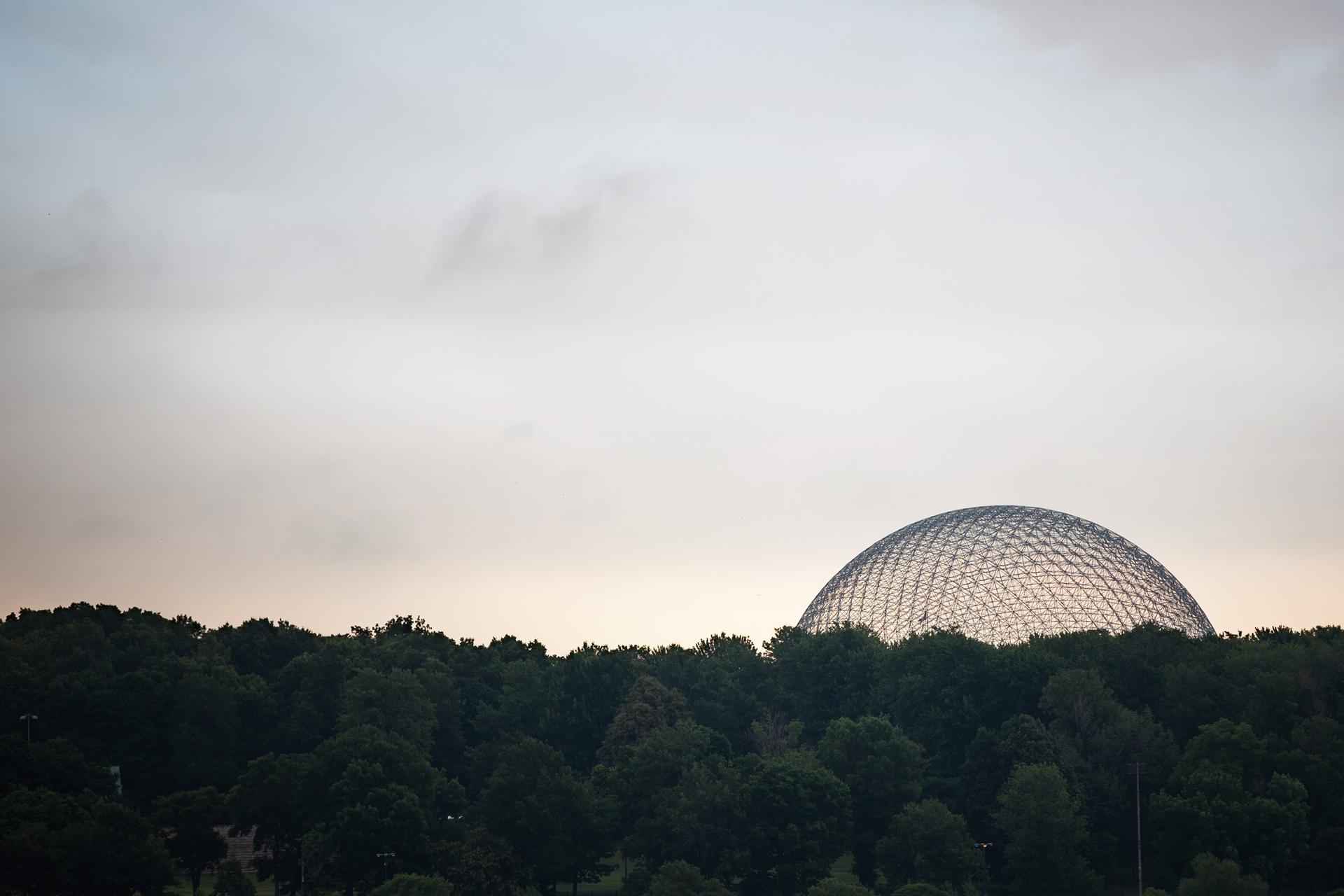 Montreal Biosphere rising above a forest of green trees
