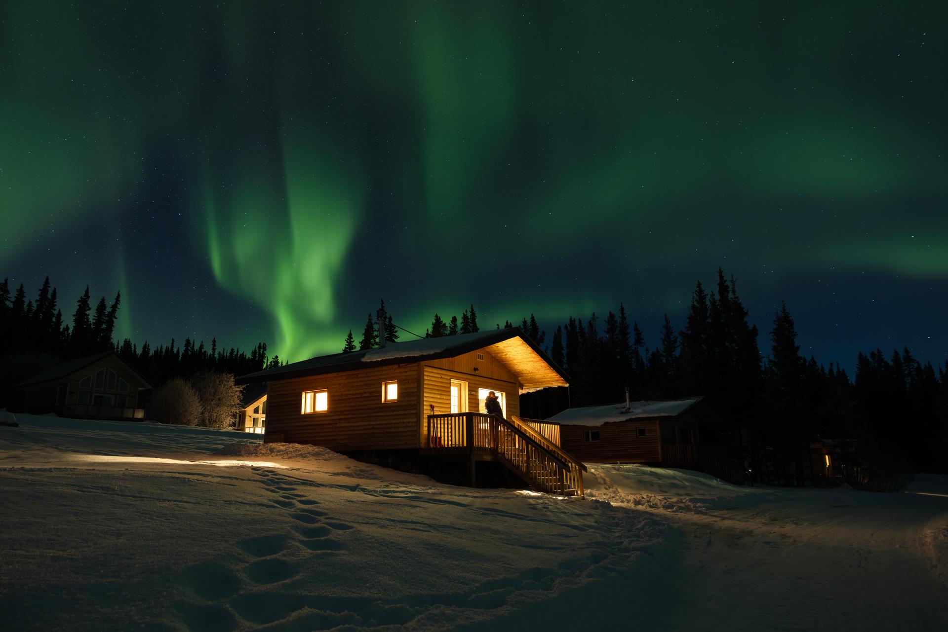 A cabin at night underneath the Northern Lights in Whitehorse, Yukon.