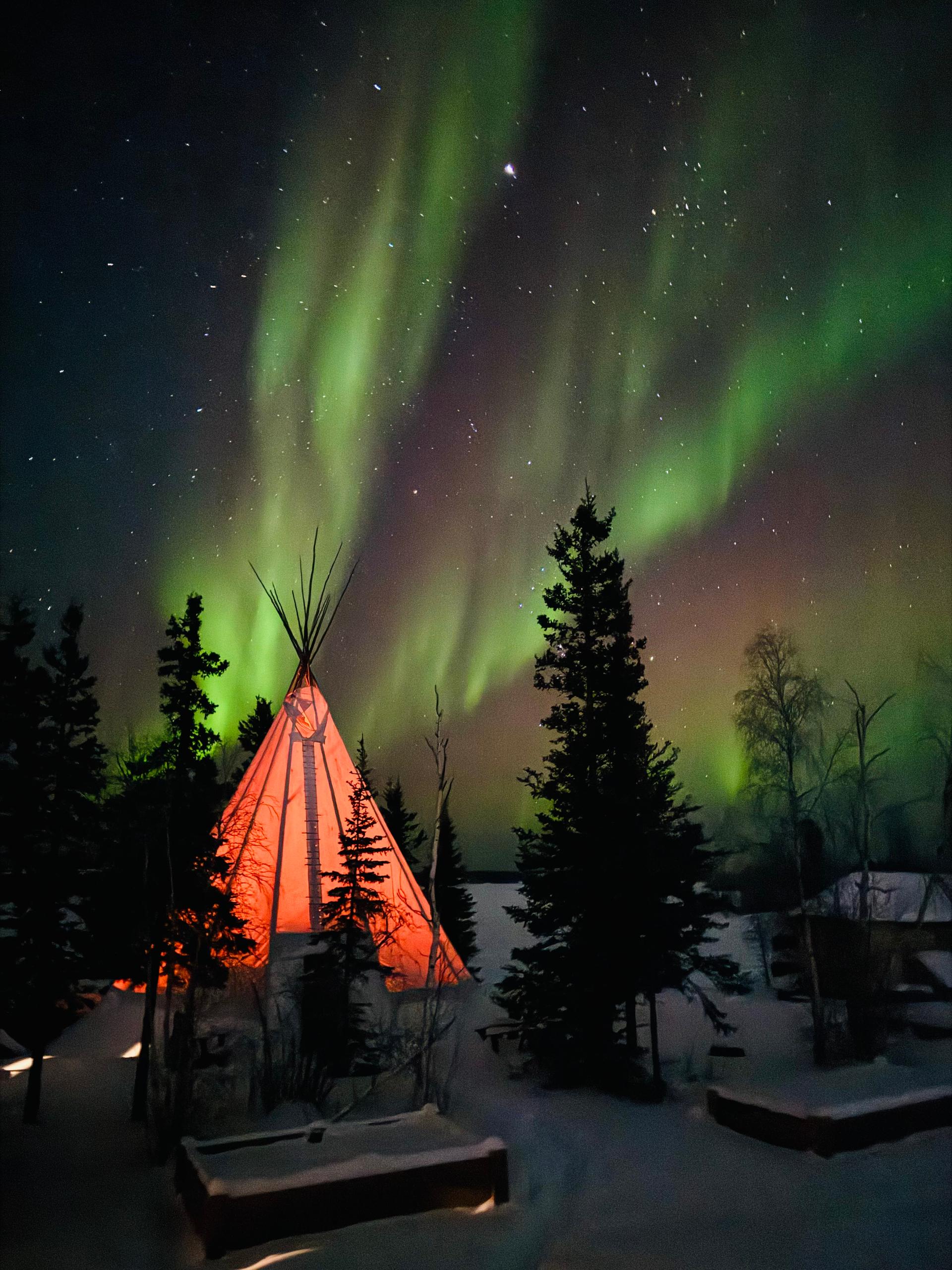 An illuminated tent under the Northern Lights in the Canadian North