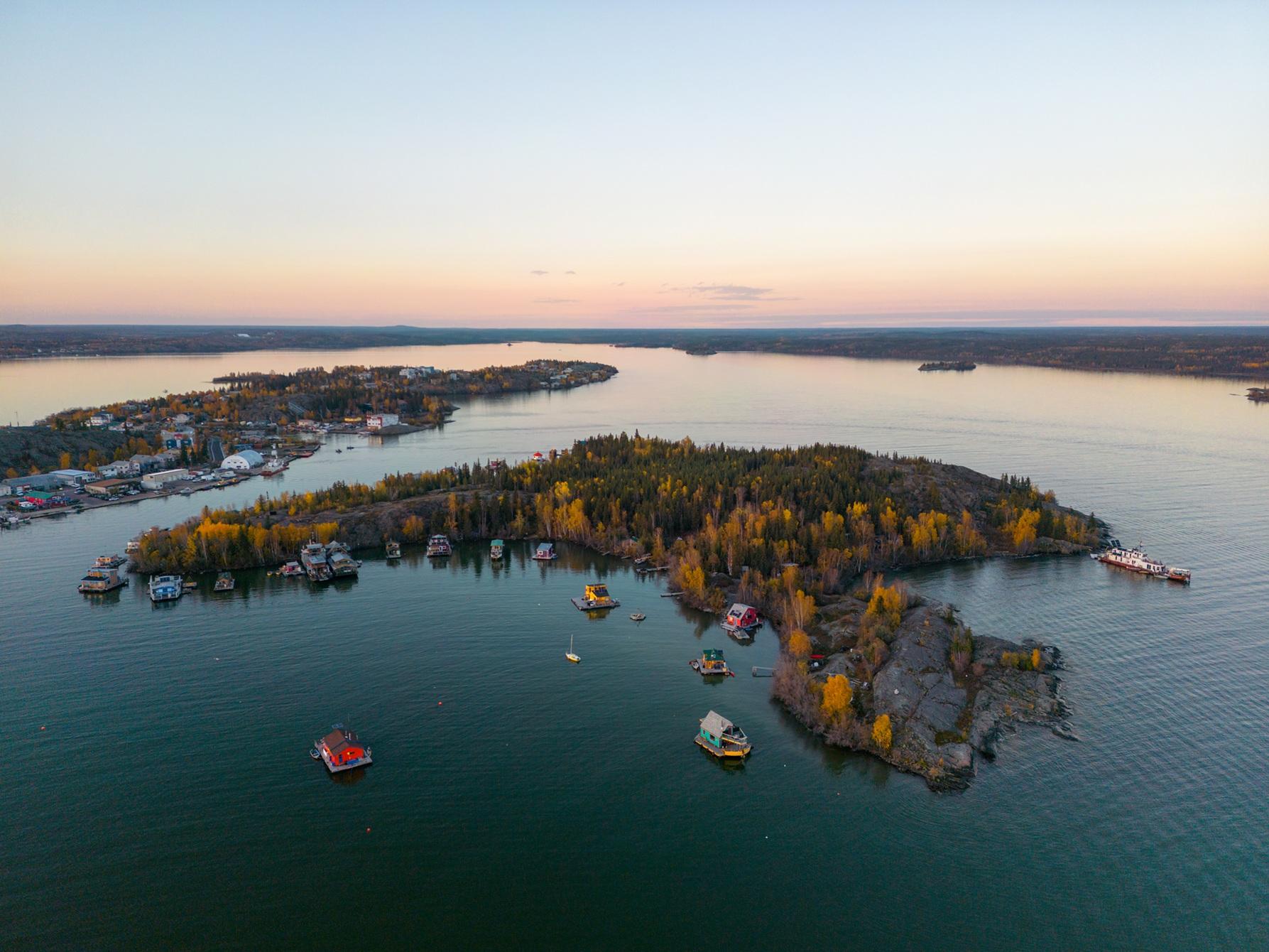 Aerial view of a lakeside community surrounded by autumn forest and water