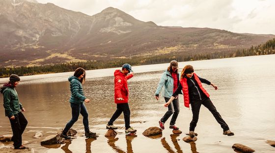 Group of people walking across rocks in a lake in Jasper Provincial Park