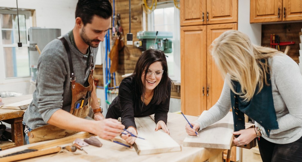 Three people crafting boards in a workshop