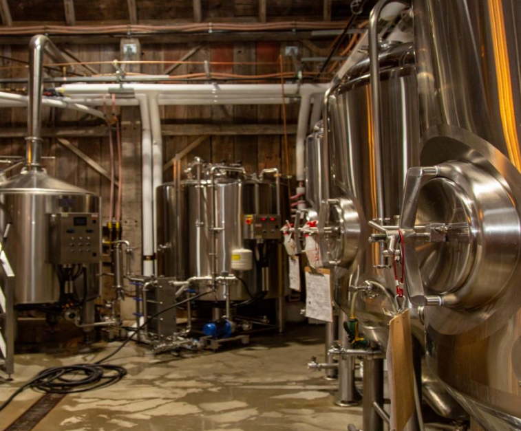  The interior of a brewery with large stainless steel fermentation tanks and brewing equipment.