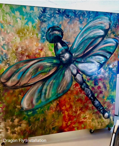 A vibrant artwork depicts a large, colorful dragonfly against a background of abstract, multicolored leaves, labeled "Dragon Fly Installation."