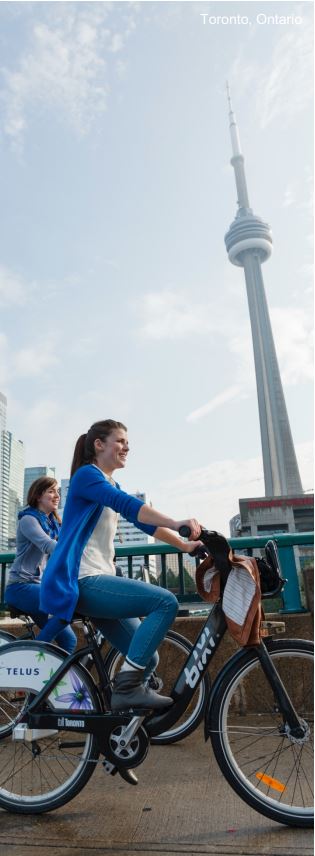 People riding bikes in front of the CN Tower in Toronto, Ontario