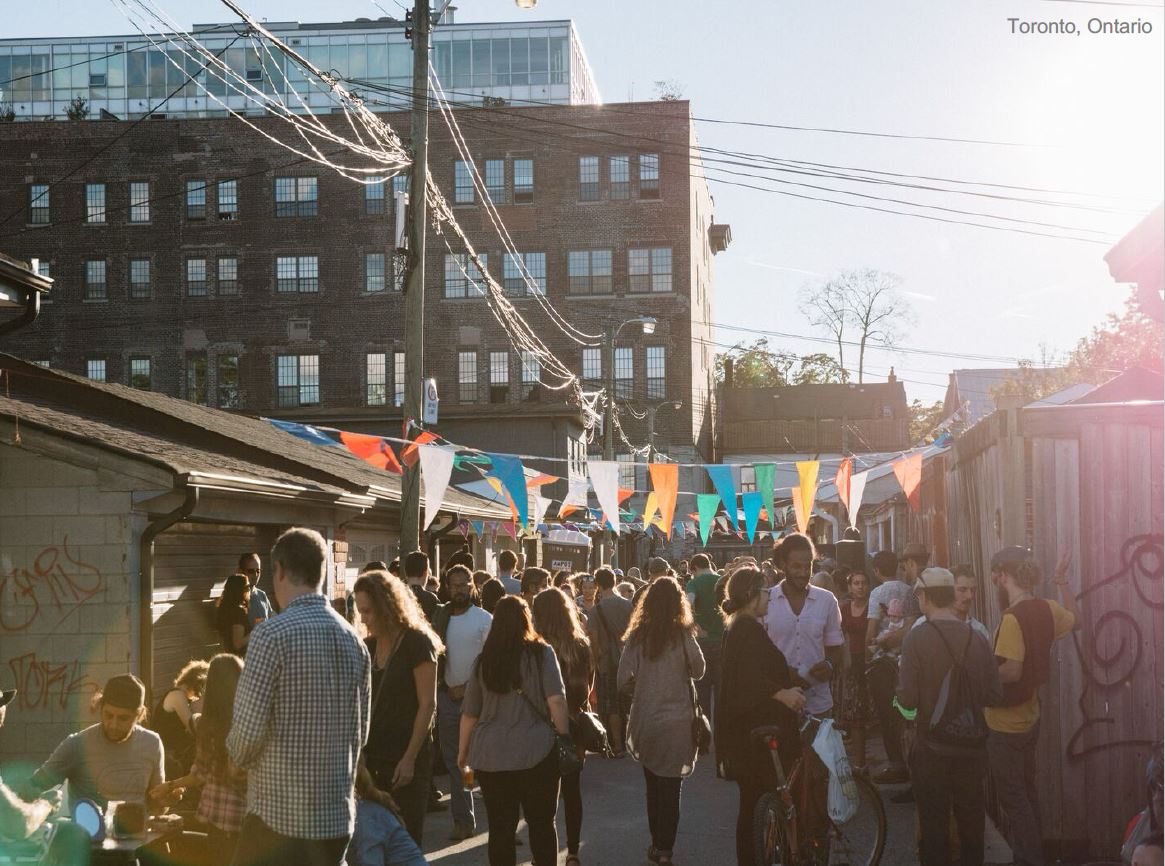 A group of people congregating in an alleyway block party in Toronto, Ontario.
